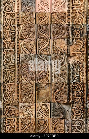 Motivi decorativi della parete del complesso Qutb a Delhi del sud, India, primo piano antiche decorazioni a bassorilievo della parete delle rovine della moschea punto di riferimento, popolare turista Foto Stock