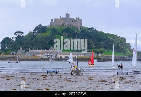 Piccole imbarcazioni a vela sulla spiaggia di Marazion e sulla baia di Mount’s con il monte di St Michael sullo sfondo, Cornovaglia occidentale, Inghilterra, Regno Unito Foto Stock