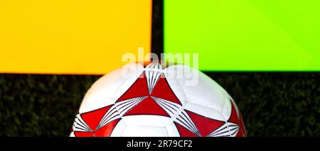 Un'immagine di una palla da calcio, illuminata su un vivace sfondo verde al neon Foto Stock