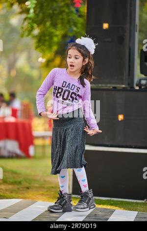 New Delhi, India - 10.12.2022 - ragazza piccola danza a musica all'aperto pista da ballo, ragazza divertente danza all'aperto festa per bambini nel cortile, felice c Foto Stock