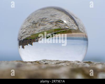 Il Castello di Bamburgh si riflette in una palla di lente, sulle pareti del castello Foto Stock