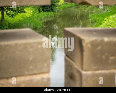 Ponte che attraversa il fiume Aln ad Alnwick, Northumberland, Regno Unito che incornicia il fiume attraverso la croce a freccia catturando i riflessi su di esso. Foto Stock