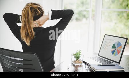 Giovane donna asiatica è seduta al lavoro e ha dolore al collo mentre è seduta in ufficio Foto Stock