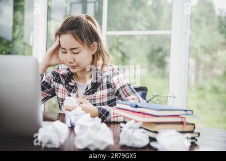 donna seduta giù, il suo volto non si è stabilizzato. Alla scrivania del computer ha mal di testa e stress. Causa di duro lavoro e riposo insufficiente. Foto Stock