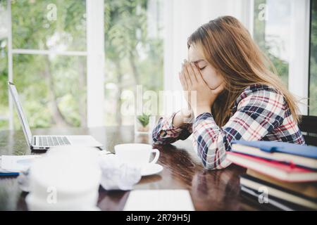 Donna d'affari stanca che lavora su un computer Ritratto di stressata giovane donna comodamente con mal di testa alla scrivania. Donna esausta di affari che lavora su lapt Foto Stock