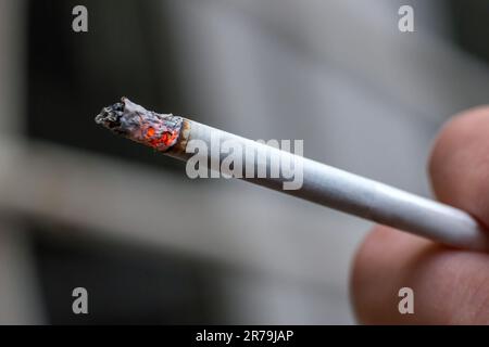 Primo piano di una sigaretta illuminata in una mano Foto Stock
