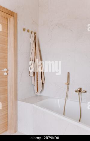 Un elegante bagno caratterizzato da pavimenti in marmo bianco con accenti in legno che creano un'atmosfera lussuosa Foto Stock