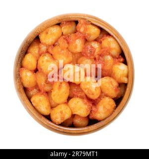 Mini gnocchi conditi in salsa di pomodoro, in ciotola di legno. Gnocchi bolliti, piccoli gnocchi italiani, di patate, farina di grano e uova, conditi con sugo. Foto Stock