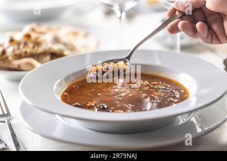 Zuppa di minestrone tradizionale italiana calda e fumante in un piatto, mangiata con un cucchiaio. Foto Stock
