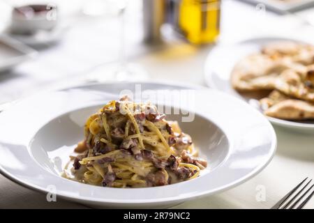 Spaghetti alla carbonara con uova, pancetta e un generoso pizzico di pepe nero. Foto Stock