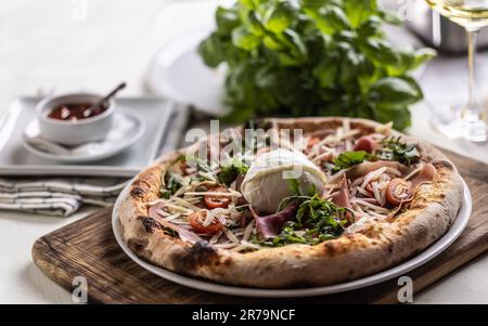 Pizza appena sfornata con prosciutto, rucola e mozzarella di bufala. Foto Stock