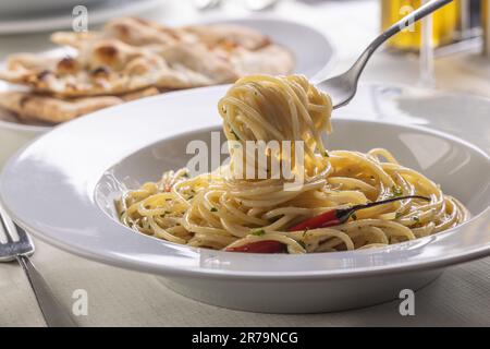 Spaghetti all'aglio e olio spinnati su una forchetta che porta fuori dal piatto una porzione boccante di pasta. Foto Stock