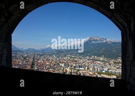 GRENOBLE, FRANCIA, 12 giugno 2023 : la città vista attraverso una cornice dalla fortezza della Bastiglia, che domina la città, con le montagne Vercors in t Foto Stock