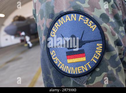 Spangdahlem, Germania. 14th giugno, 2023. Il logo del 'German F-35A Sostainment Team' è visto sulla manica di un pilota tedesco davanti ad un pilota statunitense Air Force F-35 da caccia negli Stati Uniti Air base Spangdahlem durante l'esercizio aereo "Air Defender 2023". Venticinque nazioni e la NATO partecipano all'esercizio aereo guidato dalla Germania fino al giugno 23. Secondo la Bundeswehr, sono coinvolti circa 10.000 soldati e 250 aerei. Credit: Boris Roessler/dpa/Alamy Live News Foto Stock