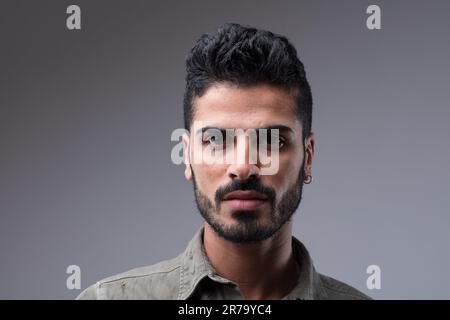 Maschio mediorientale in prima forma, il suo fascino evidente. Il ritratto frontale da primo piano mette in risalto i suoi capelli ben tenuti, la barba e il suo visage sottilmente sorridente Foto Stock