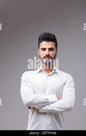 Ritratto di un uomo serio, quasi aggressivo. Bella, sottile, in una camicia bianca. Ha una barba ben curata, capelli neri, carnagione scura Foto Stock