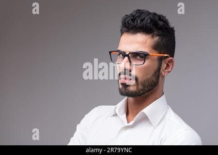 Primo piano ritratto laterale di un uomo serio, quasi aggressivo. Sottile e bello, in una camicia bianca, si accanì quasi minacciosamente. Barba ben curata, nera Foto Stock