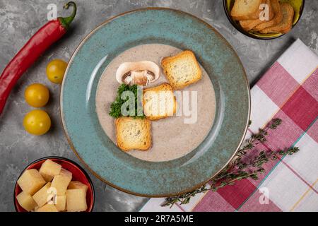 Primo piano di una ciotola di saporita zuppa di verdure, accompagnata da un lato di cracker di formaggio croccanti Foto Stock