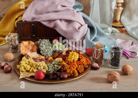 Piatto con materiale vegetale per tintura organica di tessuti sullo sfondo di cassonetto in legno con tessuti tinti a mano Foto Stock