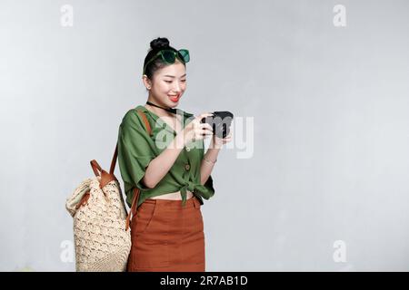 Attraente energica donna asiatica felicemente tenendo la macchina fotografica isolata su sfondo bianco Foto Stock