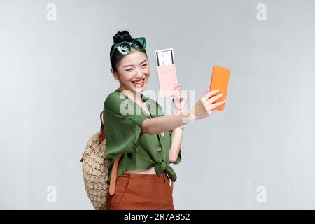 Felice viaggiatore donna con passaporto e biglietti d'imbarco prendere un selfie da smartphone Foto Stock