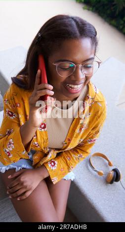 Vista dall'alto della giovane donna latino-americana che parla al telefono e ride. Spazio di copia. Foto Stock