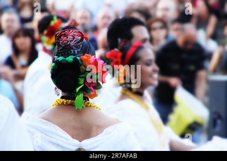 Un allegro gruppo di donne diverse che indossano sciarpe luminose e colorate che camminano insieme in una vivace strada urbana Foto Stock