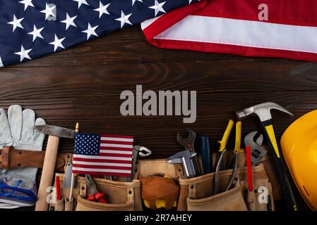 Attrezzi hardHat toolbelt e noi bandiera su sfondo di legno banner del giorno di lavoro mockup Foto Stock