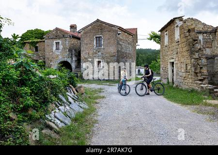 Turista esplorare tradizionale, bellissimo piccolo villaggio in pietra di abitanti nella parte slovena della penisola istriana in bicicletta, Slovenia Foto Stock