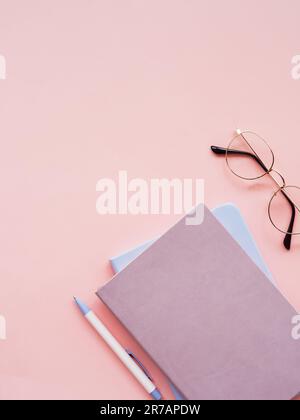 Due taccuini colorati, penna e occhiali su sfondo rosa. Business, concetto di lavoro, blog. Giacitura piatta. Spazio di copia Foto Stock