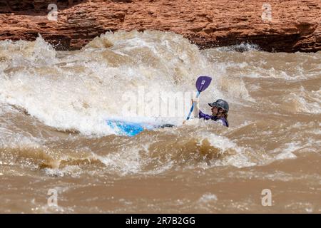 Un kayaker negozia grandi onde a White's Rapid sul fiume Colorado ad alta quota. Moab, Utah. Foto Stock