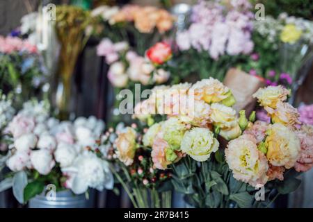 Vetrina di un negozio di fiori con grande assortimento in stile retrò. I fiori sono in secchi di metallo e vasi di vetro. Bei bouquet contro il backgroun Foto Stock