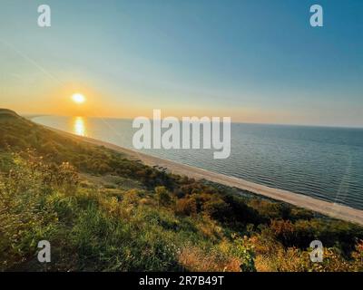 Bellissimo paesaggio con tramonto e mare. Spiaggia di sabbia con barche sulla riva. Foto Stock