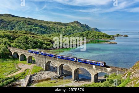 Treno Scotrail che attraversa il Viadotto di Nan Uamh all'inizio dell'estate con le acque verdi blu di Loch Nan Uamh sulla costa occidentale della Scozia Foto Stock