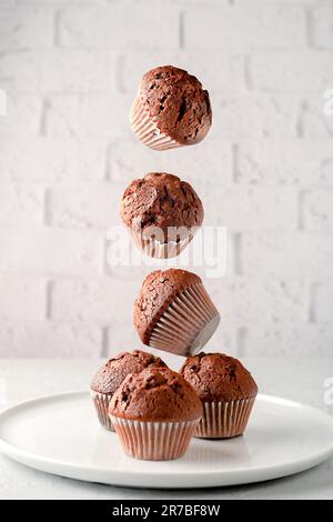 Muffin morbidi e soffici alla vaniglia con scaglie di cioccolato in fodere di carta, su sfondo rosa. Foto Stock