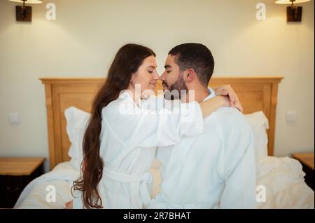 Romantico misto coppia coccole e abbracciare sul letto interno Foto Stock