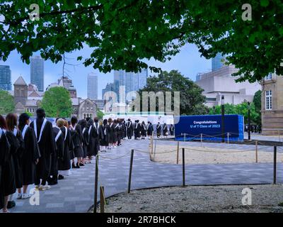 Una processione di studenti universitari laureati in abiti accademici formali va a ricevere i loro diplomi Foto Stock