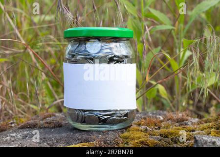 Barattolo con monete ucraine e un'etichetta bianca con posto per i supporti di testo Foto Stock