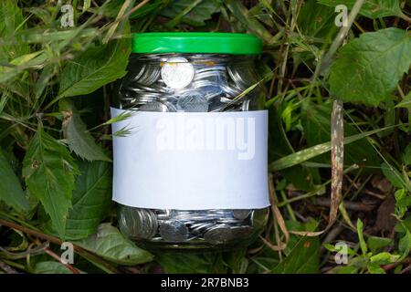 Barattolo con monete ucraine e un'etichetta bianca con posto per i supporti di testo Foto Stock