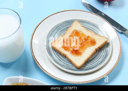 Piatto di delizioso toast con marmellata e latte su sfondo colorato, primo piano Foto Stock