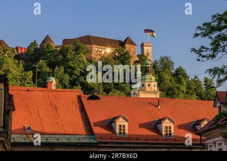 il sole tramontato in prima serata si riflette come un'esplosione di sole in una finestra del castello di ljubljiana in cima alla collina del castello Foto Stock