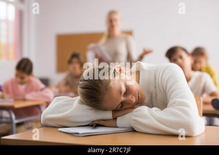 Ragazza della scuola che si trova e dorme alla scrivania Foto Stock