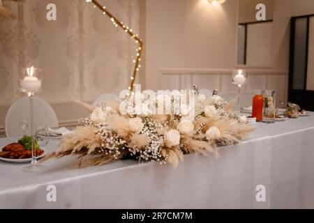 Set da tavolo per matrimoni boho. Tavolo da pranzo vintage con decorazioni, fiori e pampas in stile Boho. Set da tavolo per un evento, una festa, una data o un matrimonio. Foto Stock