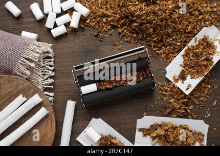 Composizione piana con rullo e tabacco su tavola di legno. Fare le sigarette arrotolate a mano Foto Stock