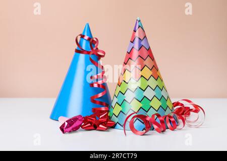 Cappelli colorati per feste, streamer e soffiatori su un tavolo bianco. Festa di compleanno Foto Stock