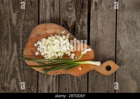 la cipolla tritata si trova su un asse di legno Foto Stock