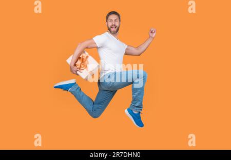 Corriere regalo a mezz'aria. Un ragazzo energico che corre veloce con la confezione regalo. Consegna di regali e regali Foto Stock