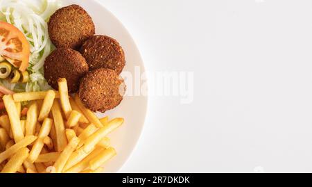 Un piatto riempito con un assortimento di salate polpette, patatine fritte e verdure assortite, pronto per essere gustato Foto Stock