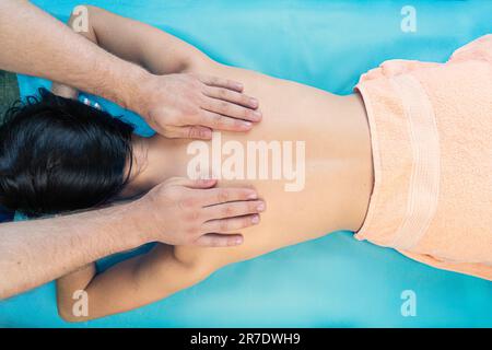 Vista dall'alto. Terapia benessere. Bella donna asiatica che fa massaggi su uno sfondo blu nel salone di bellezza. Foto Stock