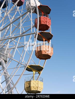 Una vista mozzafiato di una ruota panoramica con molte ruote vibranti e multicolore contro un cielo blu chiaro Foto Stock